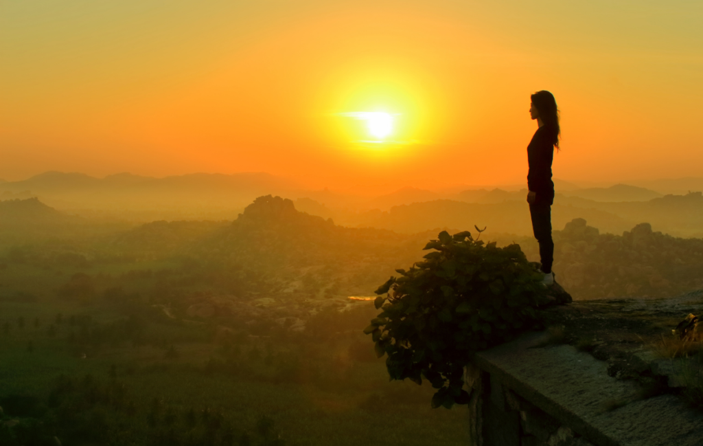 Woman standing on cliff at sunrise