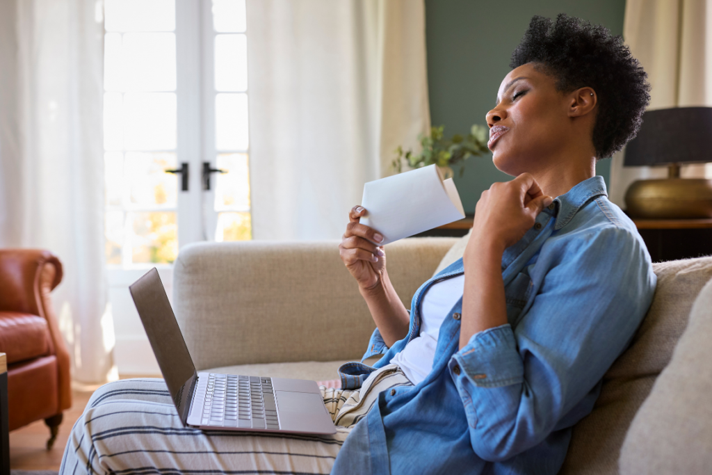 Hot flushes woman on sofa with fan and laptop